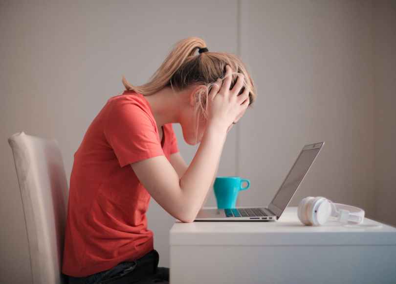 woman in red t shirt looking at her laptop