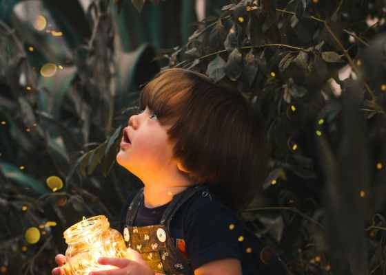 child holding clear glass jar with yellow light